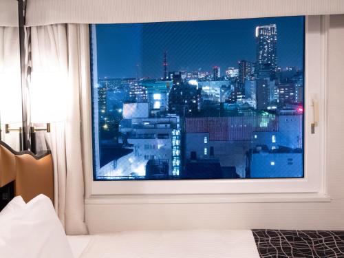 a view of a city skyline from a bedroom window at APA Hotel Shinjuku Kabukicho Chuo in Tokyo