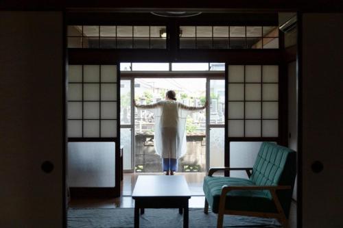 a person standing in a room looking out of a window at 島原の一棟貸し まちの宿山と朝 in Shimabara