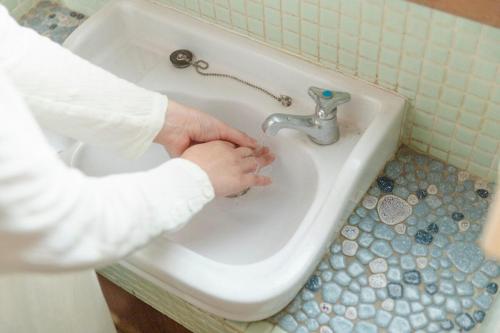 a man washing his hands in a bathroom sink at 島原の一棟貸し まちの宿山と朝 in Shimabara