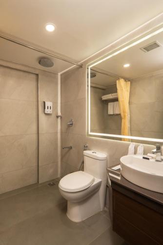 a bathroom with a toilet and a sink and a mirror at Classik Fort Inn & Suites in Cochin