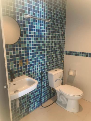 a blue tiled bathroom with a toilet and a sink at Nai Yang Guest House in Nai Yang Beach