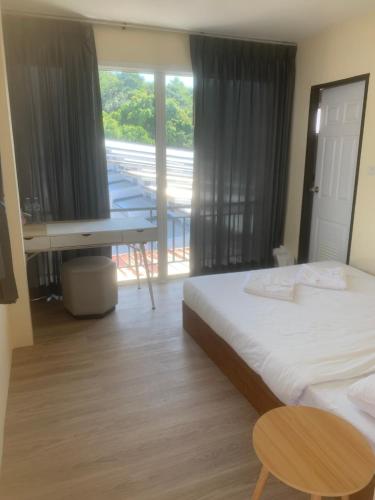 a bedroom with a bed and a desk and a table at Nai Yang Guest House in Nai Yang Beach