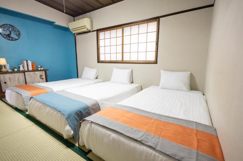 three beds in a room with a window at nestay villa osaka imazato in Osaka