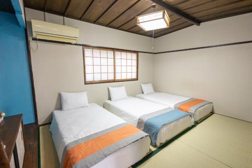 a room with two beds and a window at nestay villa osaka imazato in Osaka