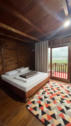 a bedroom with a bed and a rug on the floor at Padangsari Cabin House in Diyeng