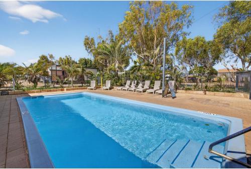 a swimming pool with lounge chairs in a resort at Discovery Parks - Carnarvon in Carnarvon