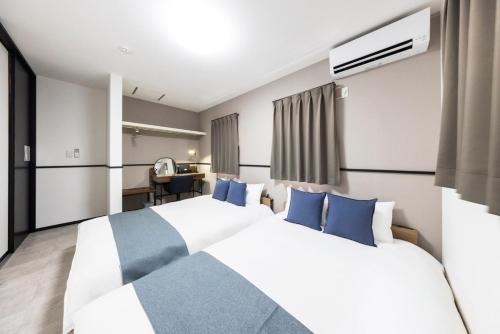 a bedroom with a large white bed with blue pillows at AMP FLAT Marron Hontosu in Tosu