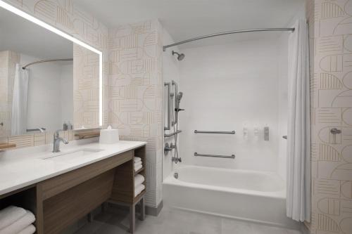 a bathroom with a tub and a sink and a shower at Home2 Suites By Hilton Syracuse Liverpool Airport Area in Liverpool