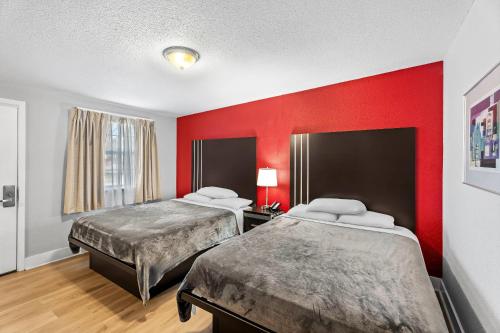 two beds in a room with red walls at Rodeway Inn Kingsland - Lake LBJ in Kingsland