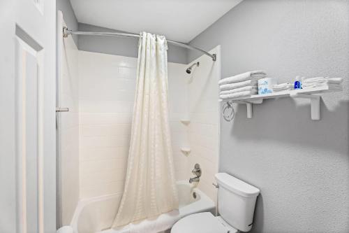 a bathroom with a shower curtain and a toilet at Rodeway Inn Kingsland - Lake LBJ in Kingsland