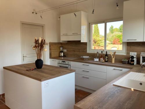 a kitchen with white cabinets and a wooden counter top at CALA CORSICA - Villas 5 Etoiles T5 Piscine privée - Villa T4 Piscine privée chauffée - Villa T3 Piscine partagée - Internet Fibre - Entièrement Climatisée à Lecci de Porto-Vecchio Cala Rossa in Lecci