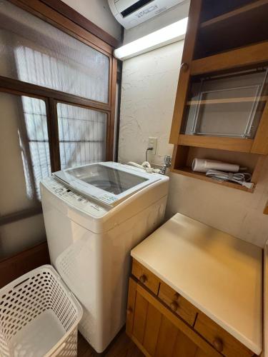 a small kitchen with a washing machine in a room at ゲストハウス あしもり in Okayama