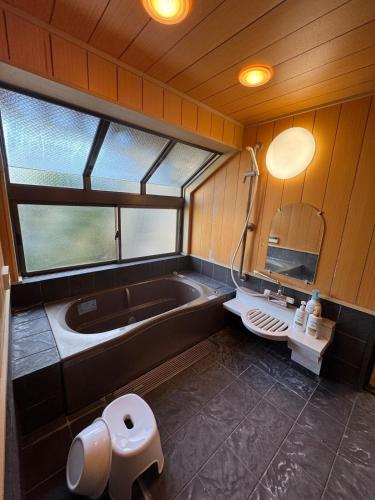 a bathroom with a tub and a toilet and a sink at ゲストハウス あしもり in Okayama