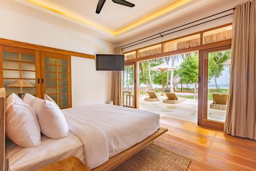 a bedroom with a bed and a sliding glass door at Villa Madu Mentawai in Katiet
