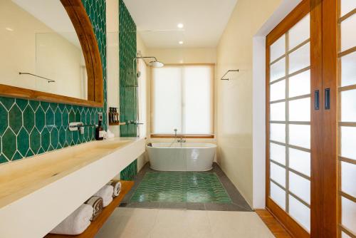 a bathroom with a tub and a green wall at Villa Madu Mentawai in Katiet