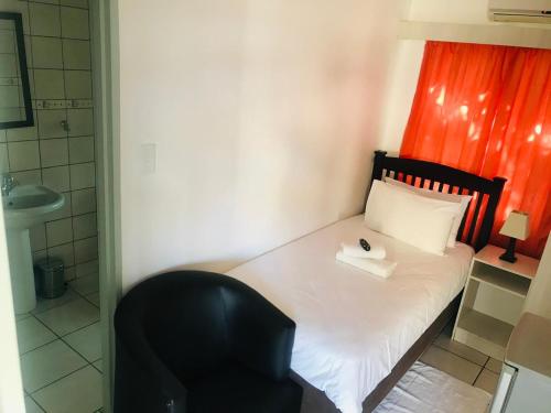 a small bedroom with a bed and a chair at Nala Guesthouse in Ellisras