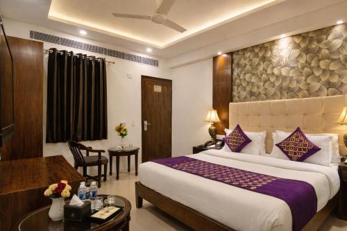 a hotel room with a large bed and a desk at The Yuvraj By LIVIQ in New Delhi