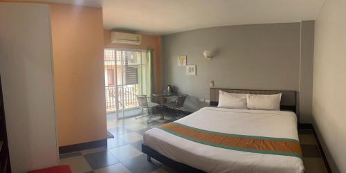 ein Schlafzimmer mit einem Bett, einem Tisch und einem Fenster in der Unterkunft Nasa Hotel in Phuket