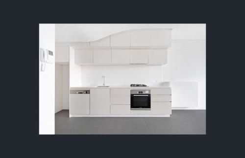 a kitchen with white cabinets and a stove top oven at Luxe 1 BR Retreat Lake Views at Nishi New Acton Canberra City in Canberra