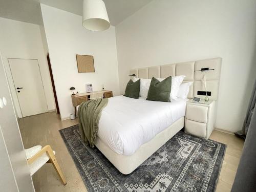 a bedroom with a large white bed with green pillows at Beautiful condominium with jacuzzi in Brussels