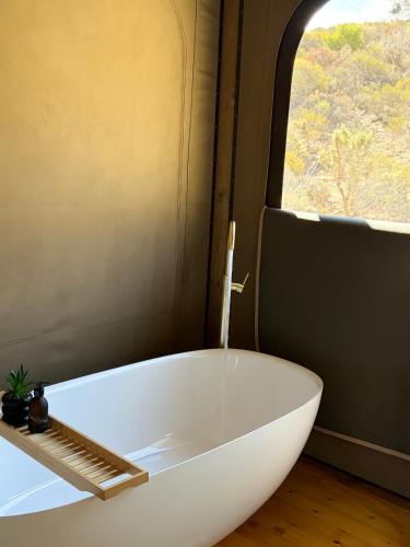 a white bath tub in a room with a window at Oudemuur Glamping in Montagu
