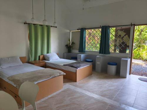 a room with two beds and a chair and windows at Niyang Siam House in Nai Yang Beach