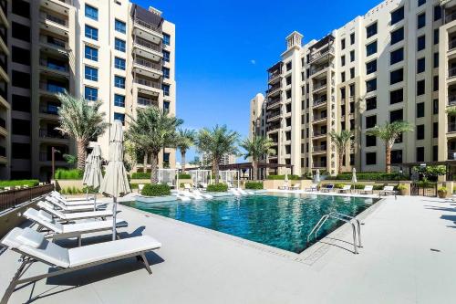 a swimming pool with lounge chairs and buildings at Asayel Apartments in Dubai