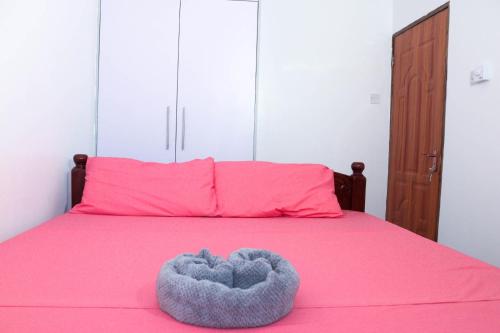 a pink bed with a heart shaped pillow on it at Raels home in Mombasa