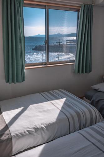 a bedroom with a bed and a large window at 波音ハウス湯河原ー心地よい波Waveの音に包まれる癒しの別荘BBQ可 in Yugawara