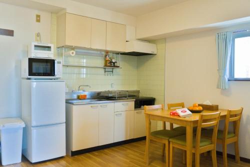 a kitchen with a table and a white refrigerator at Nishibi in Tokyo