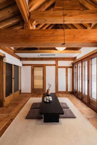 a living room with a black table and wooden ceilings at Luxury Hanok Sangseon Heritage Hanok-W in Cheongju