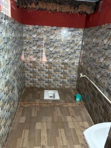 a bathroom with a stone wall and a toilet at SS Aadhya Retreat in Payikāpuram