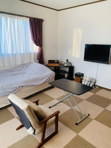 ein Schlafzimmer mit einem Bett, einem Tisch und einem Stuhl in der Unterkunft れのん in Okazaki