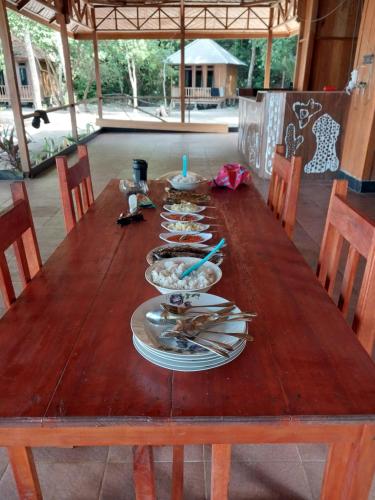 a wooden table with plates and bowls of food on it at Togean Pulotiga Resort in Popolii