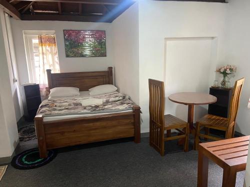 努沃勒埃利耶Ruchi House的一间卧室，里面有一张床、一张桌子和几把椅子。