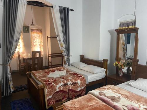 努沃勒埃利耶Ruchi House的客房设有三张床和一张带镜子的桌子