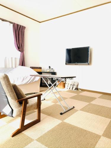 een slaapkamer met een bed, een bureau en een tv bij れのん in Okazaki