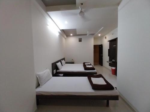 two beds in a room with white walls at Hotel Jawahar Palace in Bhusāwal