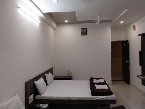 a bedroom with a bed and a white wall at Hotel Jawahar Palace in Bhusāwal