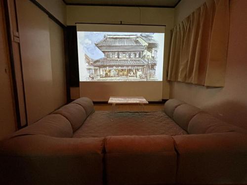 a living room with a couch in front of a screen at Kawagoe Cinema & Game House for 14 Parking in Kawagoe