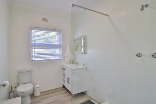 a white bathroom with a toilet and a sink at On the Rocks in Yzerfontein