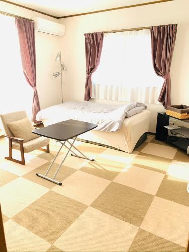 een slaapkamer met een bed, een tafel en een raam bij れのん in Okazaki