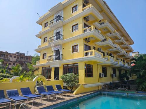 een geel gebouw met stoelen naast een zwembad bij Sonikas Leisure in Candolim