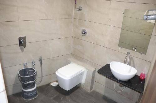 a bathroom with a sink and a toilet and a mirror at HOTEL RAJPATH Inn in Mahesāna