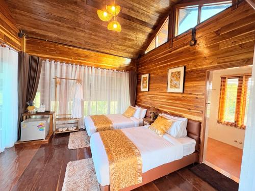 twee bedden in een kamer met houten wanden bij Chewavethee Herb Wellness Stay in Ban Chae Phang (1)