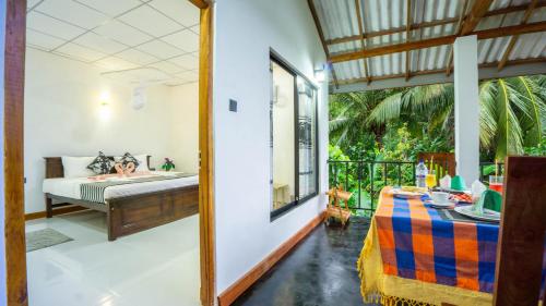a bedroom with a bed and a balcony with a woman in a tub at Isuru Homestay Pidurangala in Sigiriya