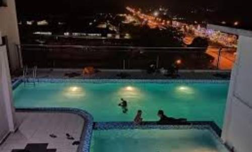 a swimming pool with people in the water at night at Amin Studio Apartment Pool And Netflix in Gua Musang