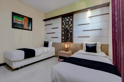 two beds in a room with white and black at Collection O near Stadion Manahan formerly Graha Laweyan Solo in Bonorejo