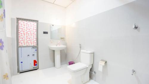 a white bathroom with a toilet and a sink at Isuru Homestay Pidurangala in Sigiriya