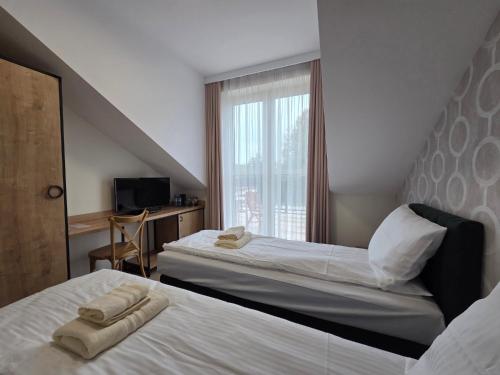 a hotel room with two beds and a window at Stay at Royal Kraków Golf in Ochmanów